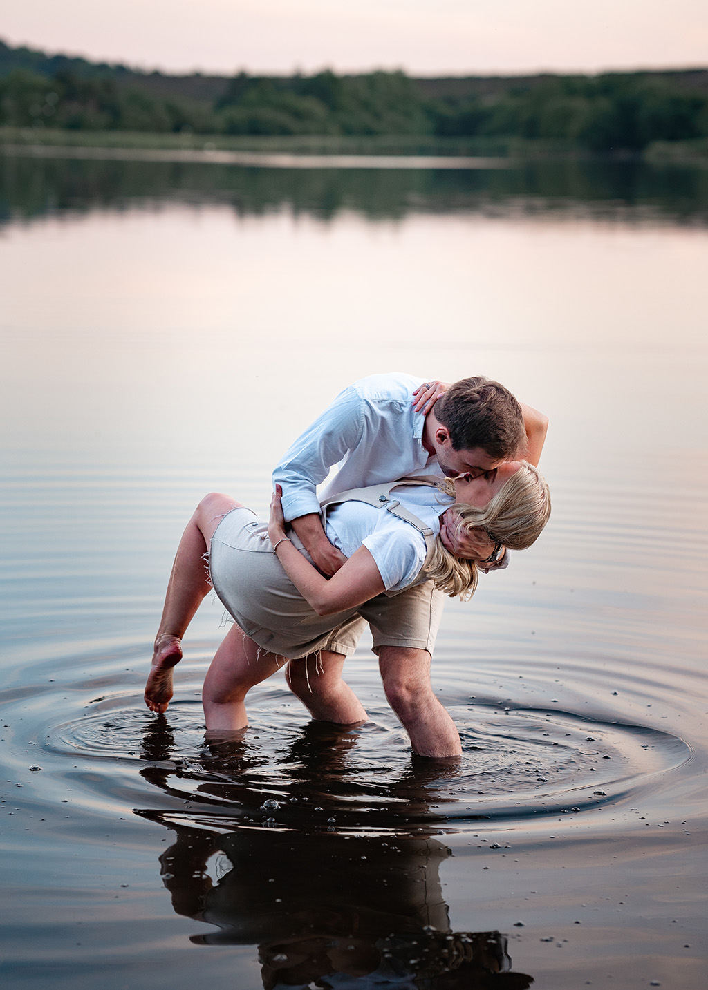 engaged couple kissing in sunset river