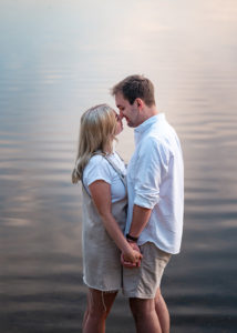 couple almost kissing in water at sunset at pre-wedding photoshoot in hampshire