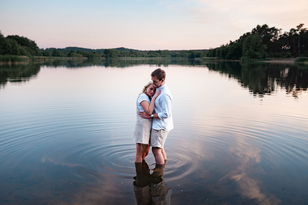 couple stood in water hugging at sunset