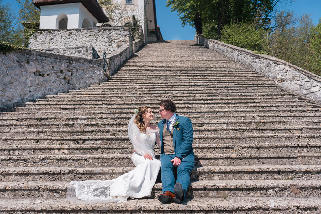 Bride and Groom on Lake Bled Island, sat on steps during wedding at Lake Bled
