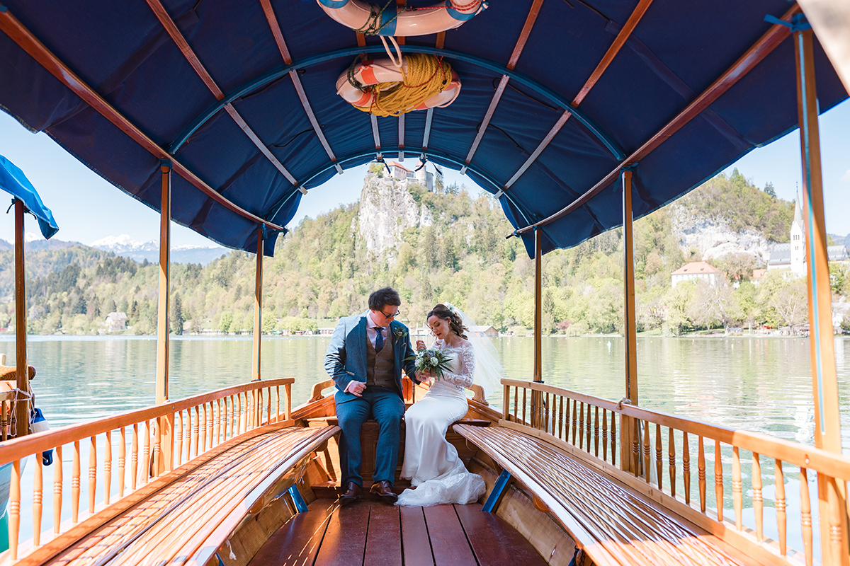Bride and Groom sit together on traditional Pletna boat in Slovenia