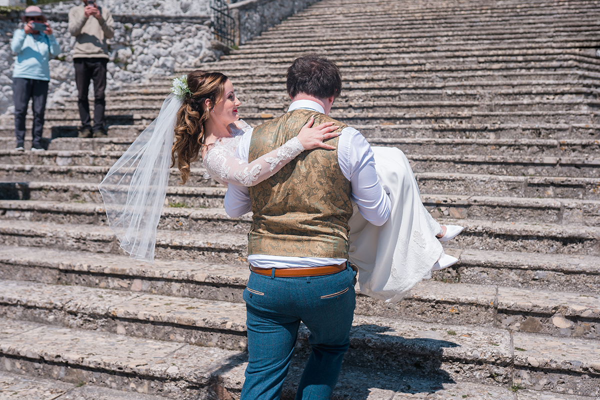 Groom carrying bride up steps on Lake Bled Island