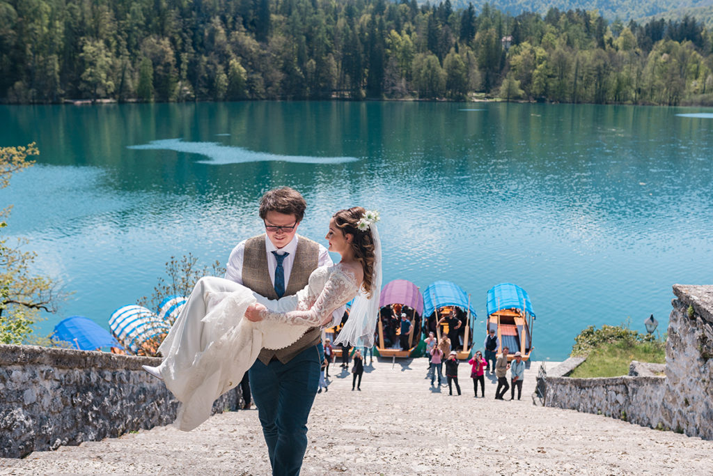 Groom carrying Bride up stairs at Lake Bled Wedding 