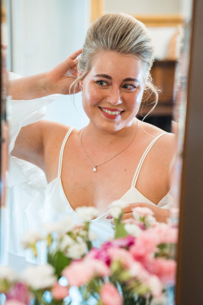 bride looks at self in mirror and touches hair