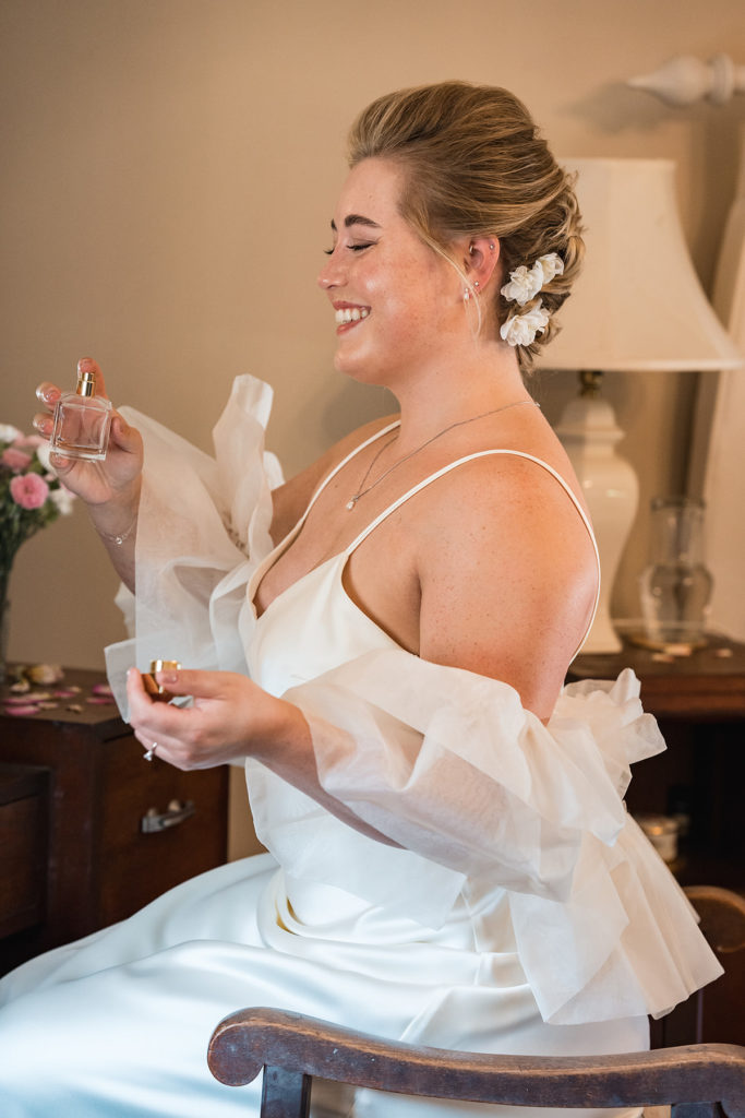 bride puts on perfume whilst smiling 
