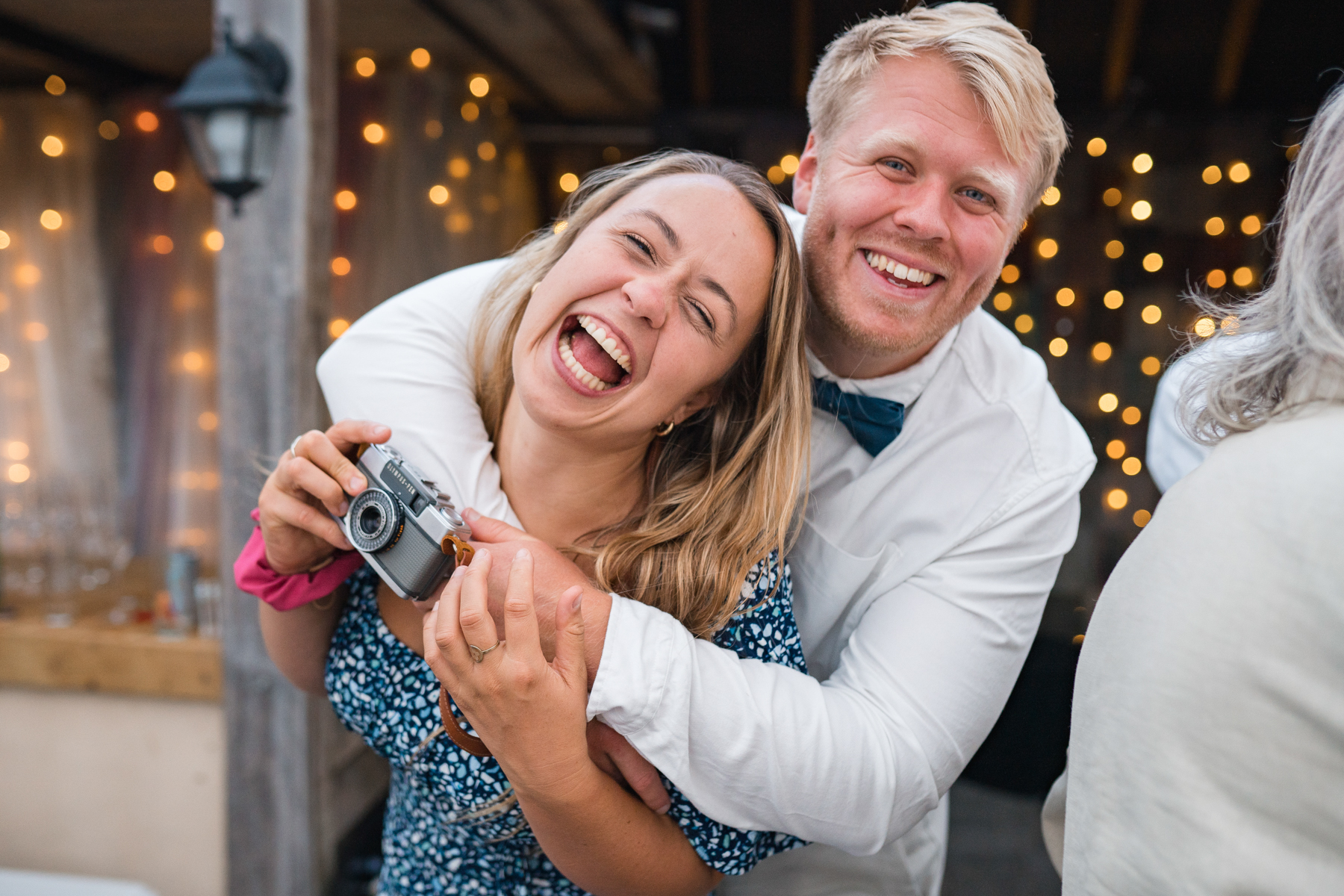 wedding guests hug and laugh towards camera 