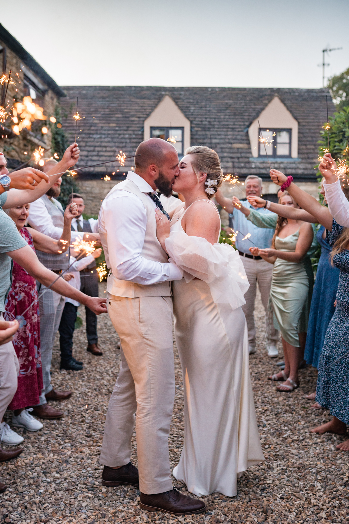 bride and groom kiss with sparklers around them