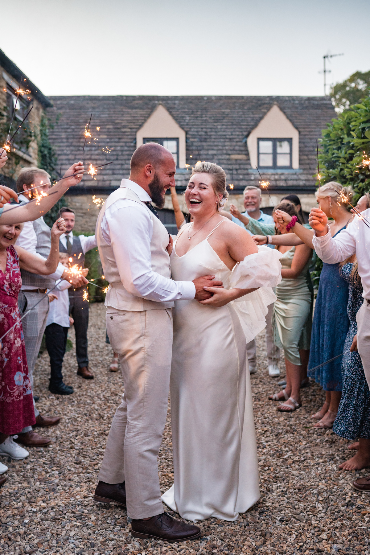 bride and groom laugh with sparklers around them