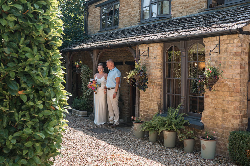 bride and father wait to walk down aisle in oxfordshire cottage wedding
