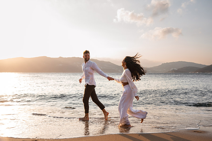 couple run along the beach at sunrise at engagement photoshoot 