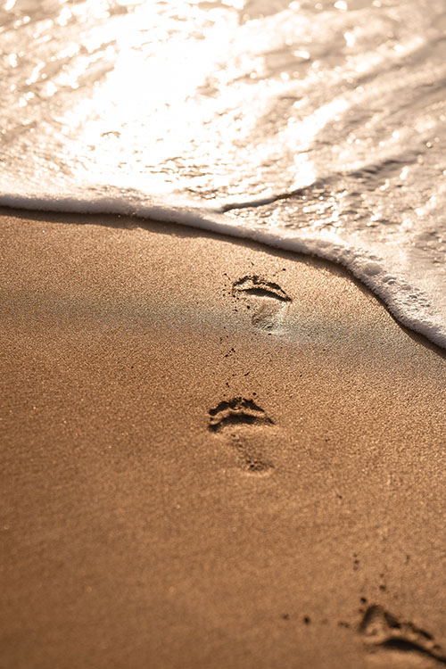 footprints in the sand on beach engagement shoot 