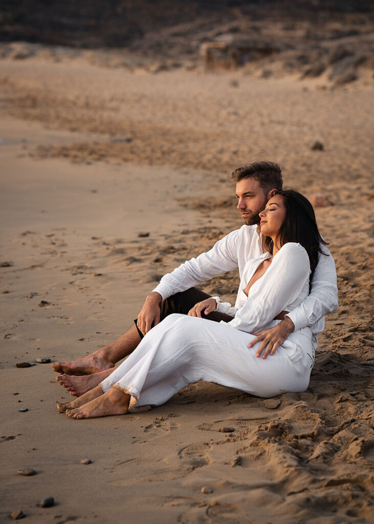 couple cuddle on a sandy beach in greece