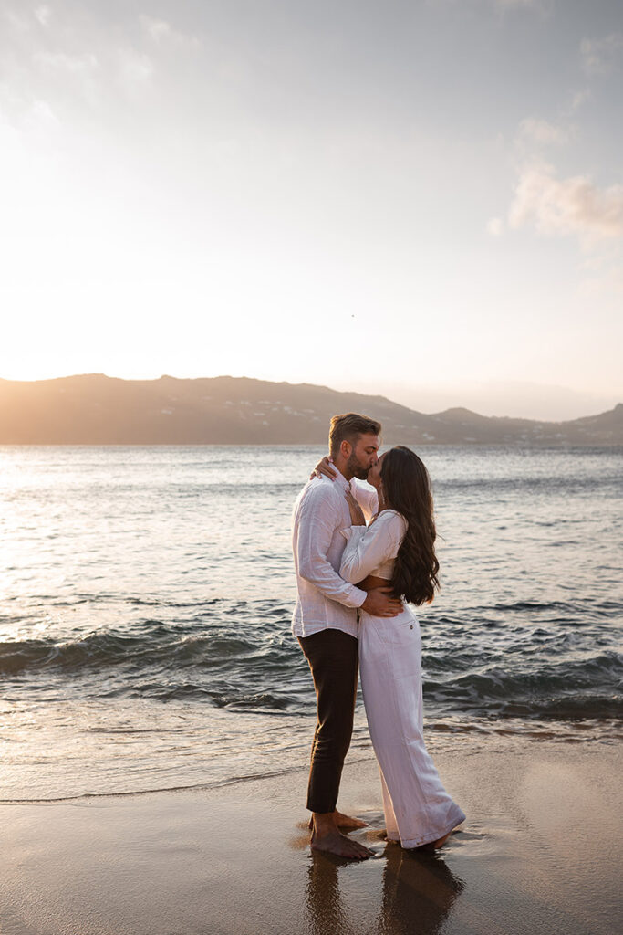 couple kiss on sandy beach in mykonos photoshoot