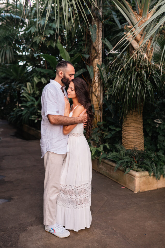Couple cuddle at engagement photoshoot in KEW Gardens Palm House