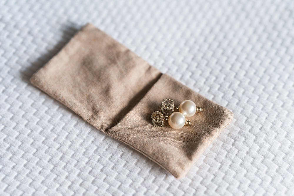 Bride has Gucci earrings placed on bed on wedding day