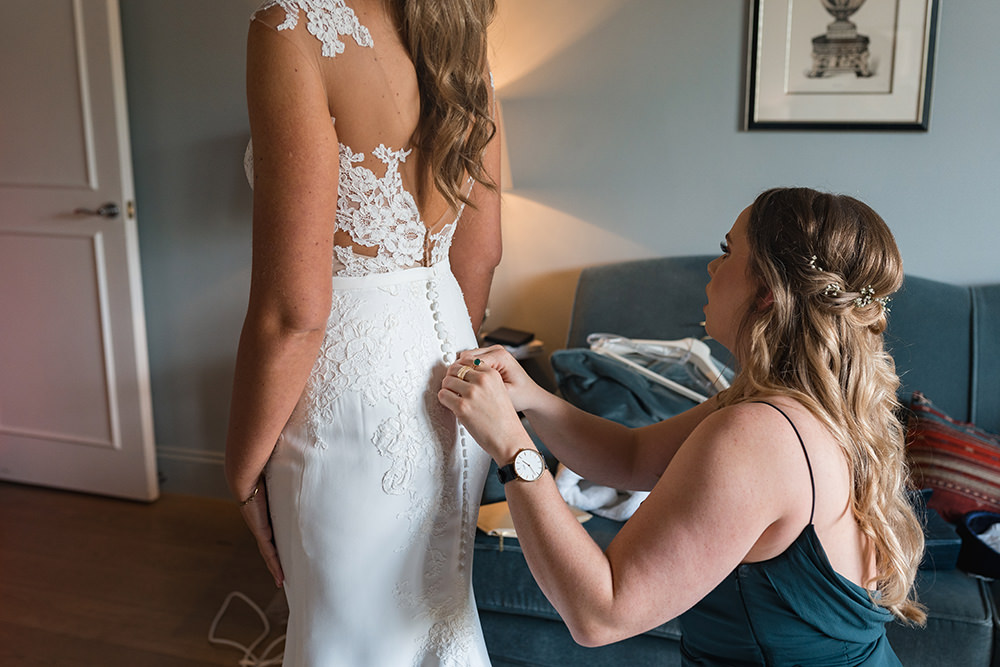 bridesmaid helping bride with shoes in black and white photo