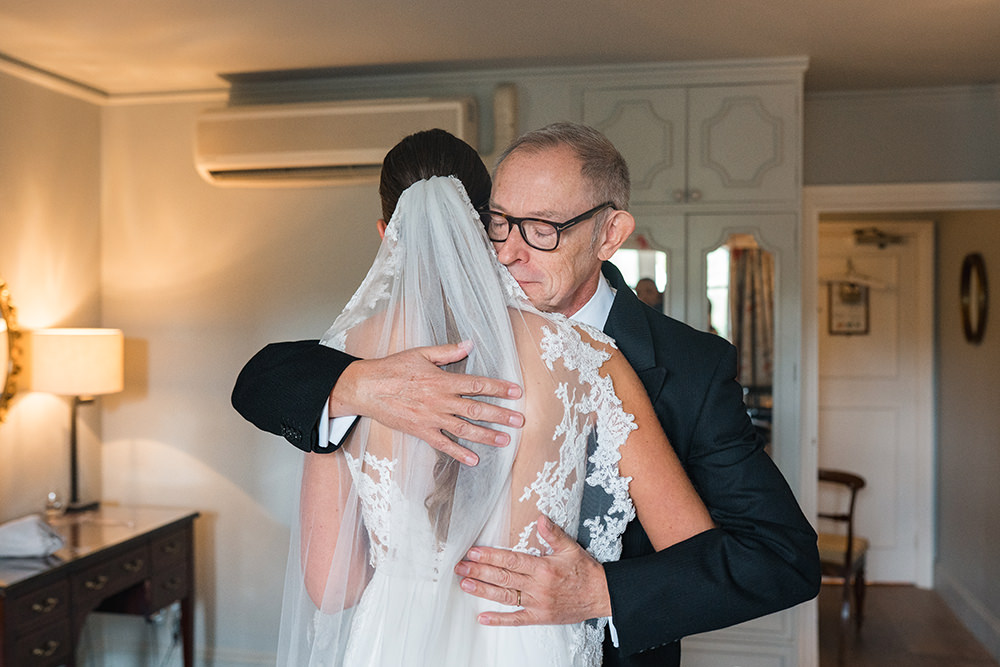 father of the bride and bride embrace in Bridal prep room at Chewton Glen before wedding ceremony