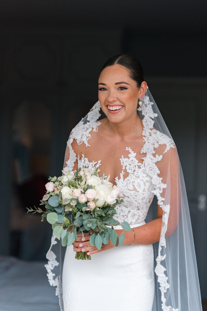 bride standing in natural light in modern wedding dress, she holds a white and blush bouquet