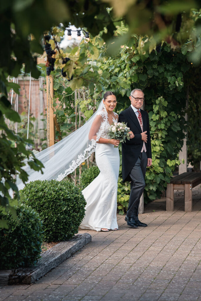 bride and father walk down the aisle at secret garden ceremony at chewton glen