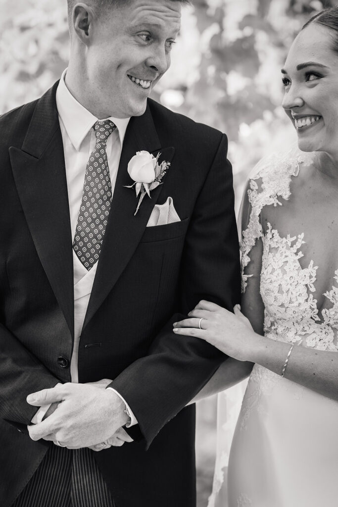 bride and groom smile at eachother in black and white photograph of chewton glen wedding