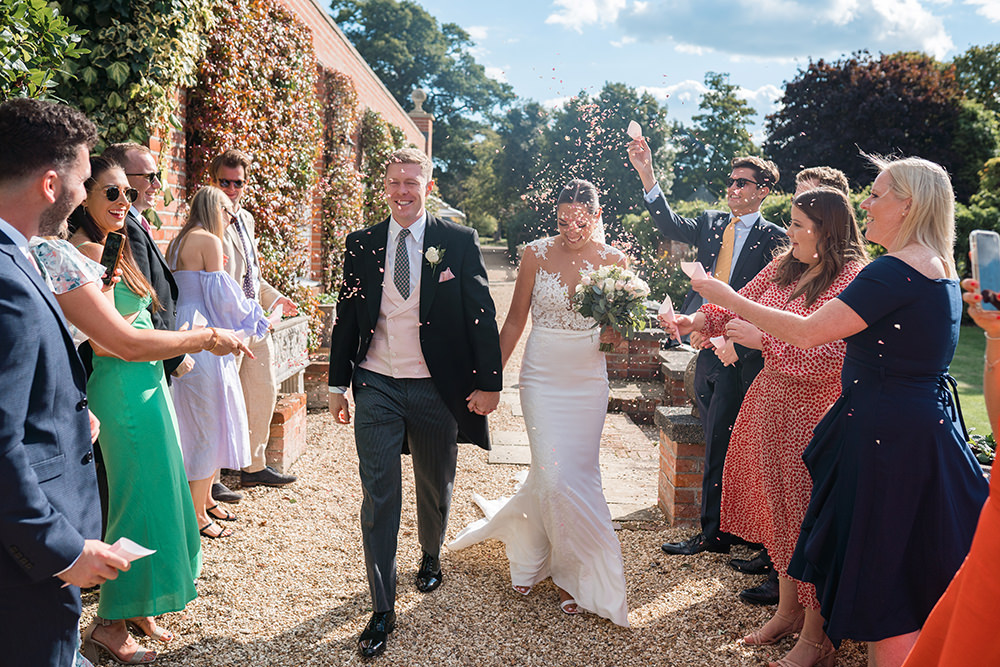 Bride and Groom walk through tunnel of guests ready to throw confetti