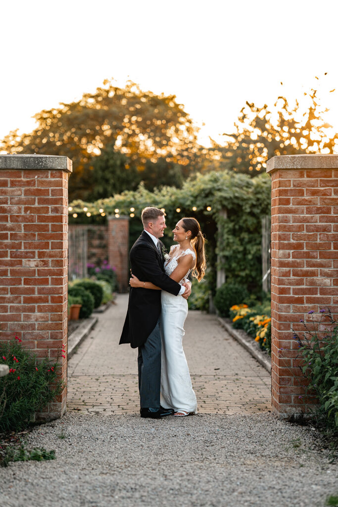 Bride and groom stand in golden light in Chewton Glen Wedding Garden
