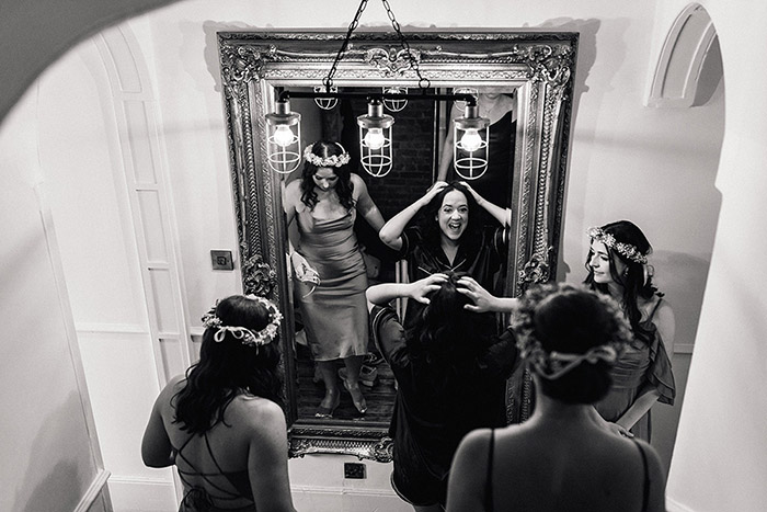 bridesmaids and bride looking in mirror laughing