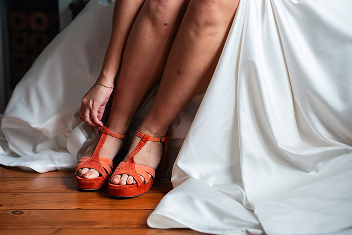 close up of bride doing up her orange shoes