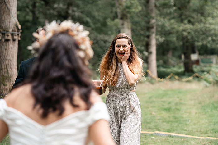 wedding guest puts hand to face and gasps as she sees the bride