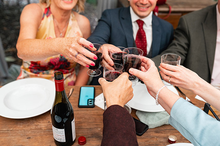 wedding guests cheers with glasses of red wine