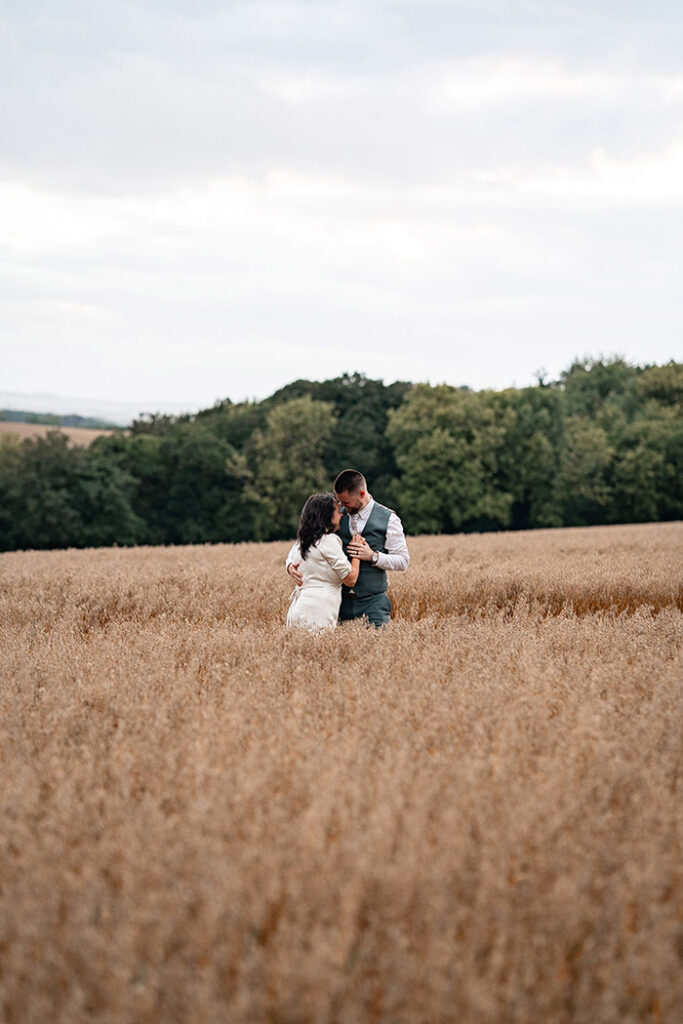 newly wed couple walking through wheat field at Harewood Forest Wedding