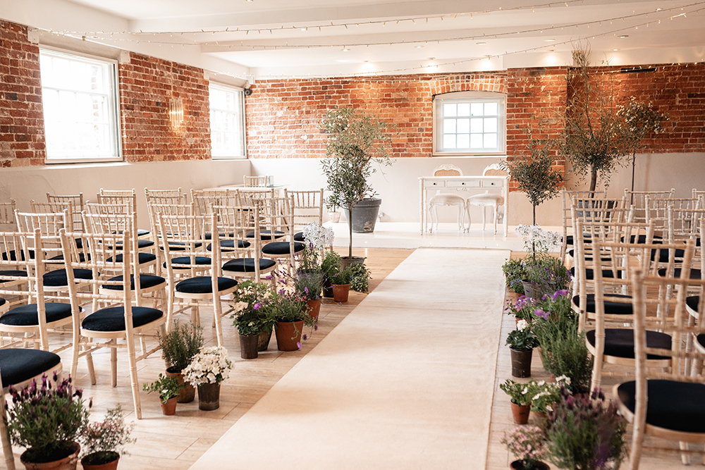 Sopley Mill's ceremony room, the granary with potted plants lining the aisle