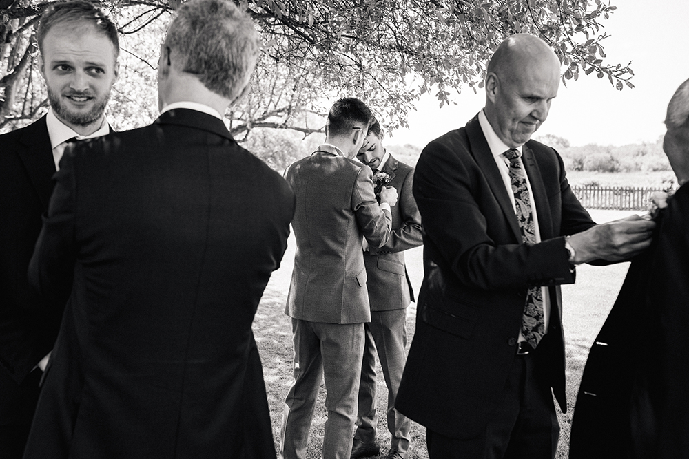 black and white photo of groom, his best man, dad and grandparents putting on their button holes