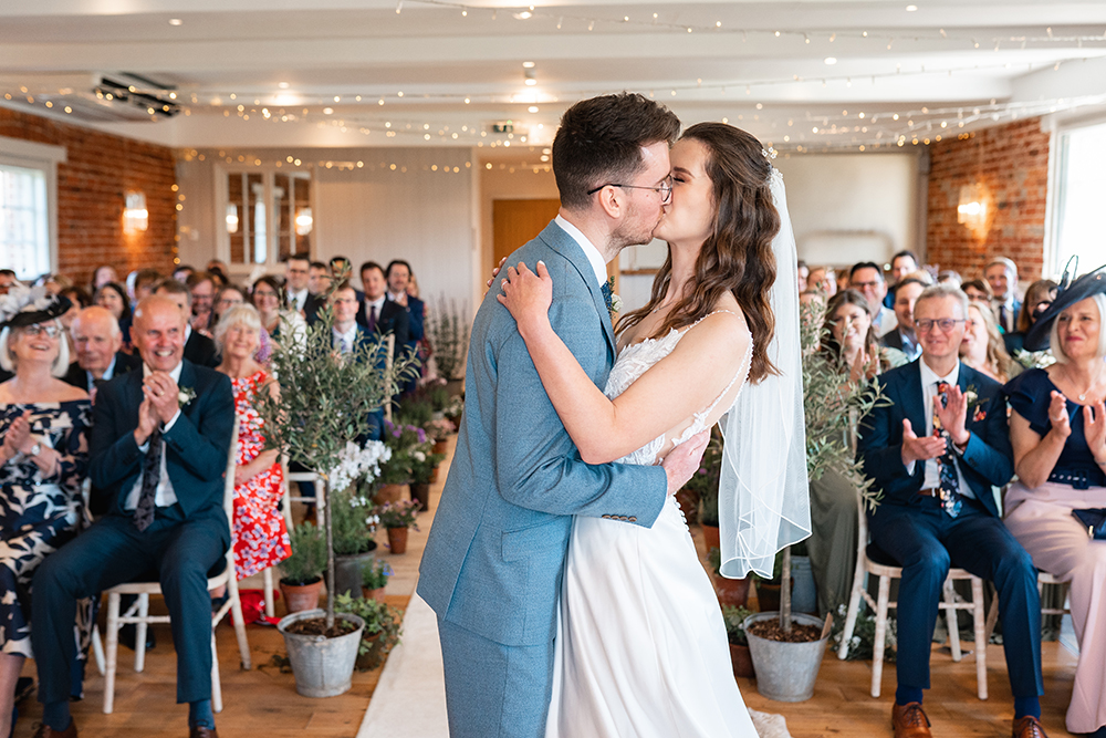 newly wed couple kiss in the Granary room at Sopley Mill