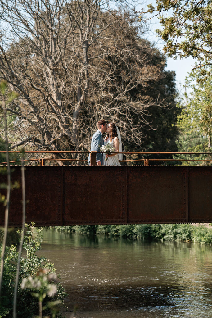 Bride and Groom stand on Iron bridge at Sopley Mill summer wedding