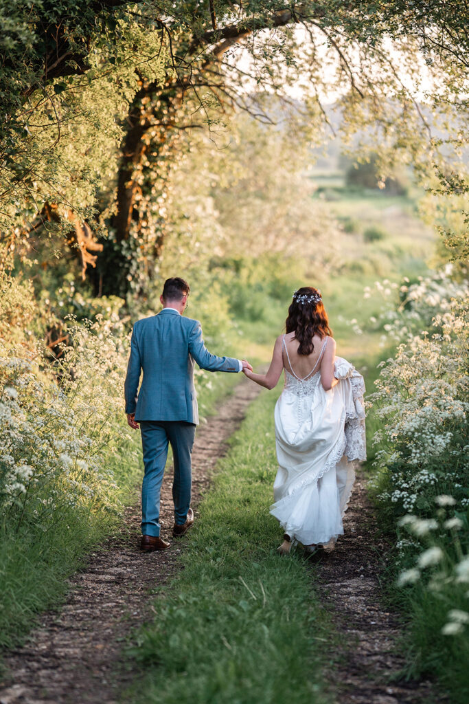 bride and groom smiling at camera, embracing each other in wild flower meadow at sopley mill