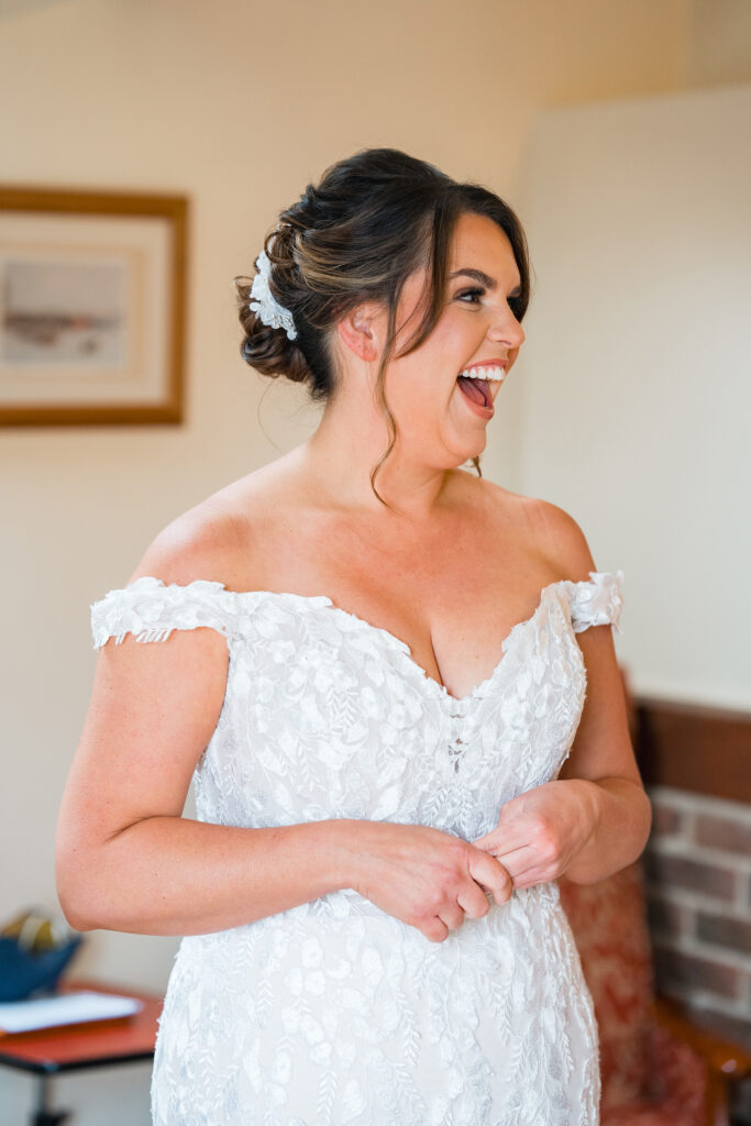 Bride in lace dress laughing at barn wedding