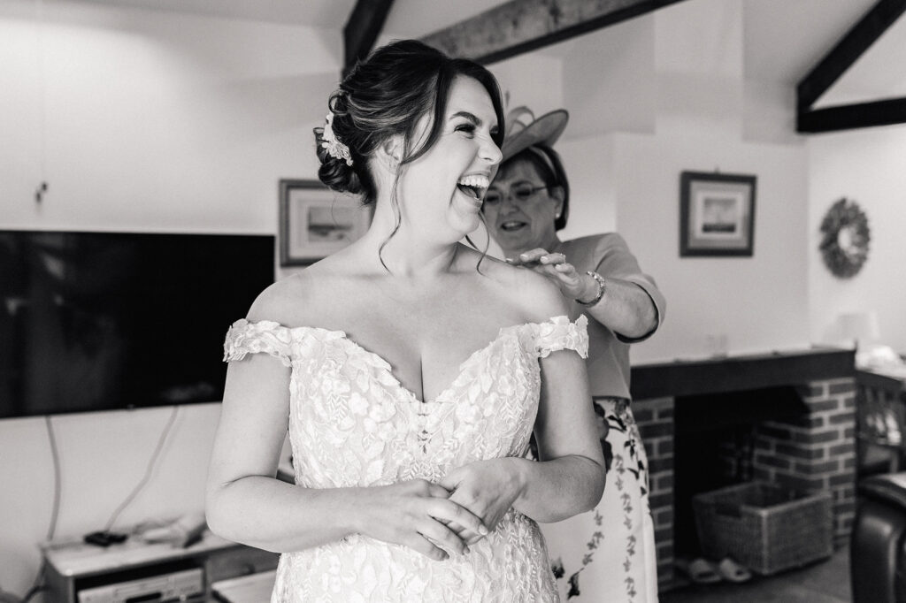 Bride in lace dress laughing at barn wedding in Black and White
