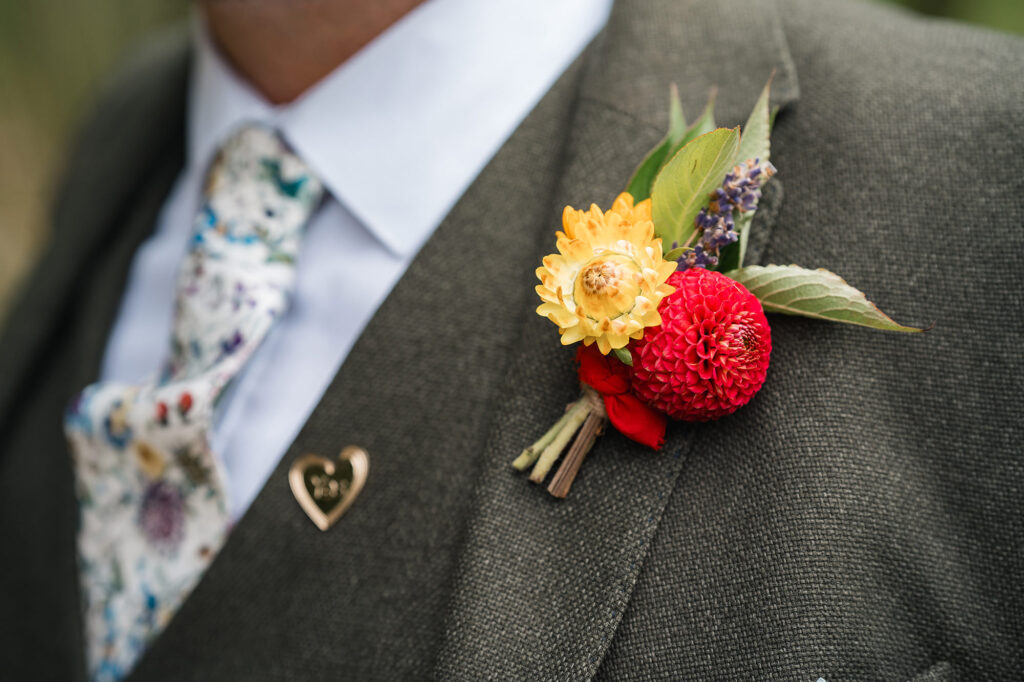 Close up of colourful buttonhole at rustic barn wedding