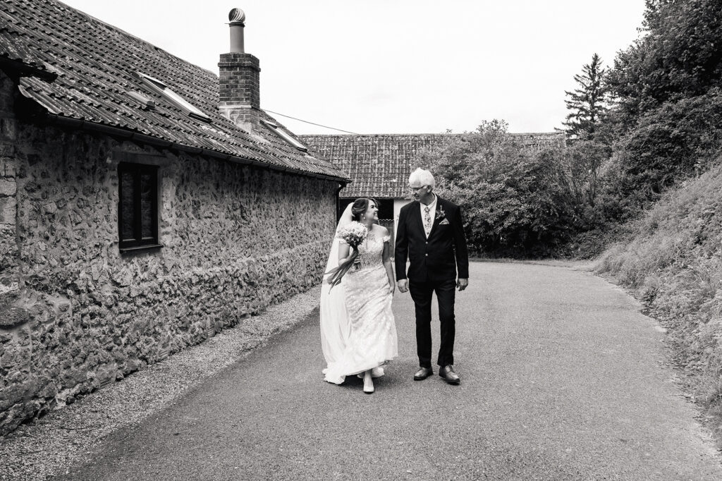 black and white portrait of bride and father smiling at eachother before walking down the aisle