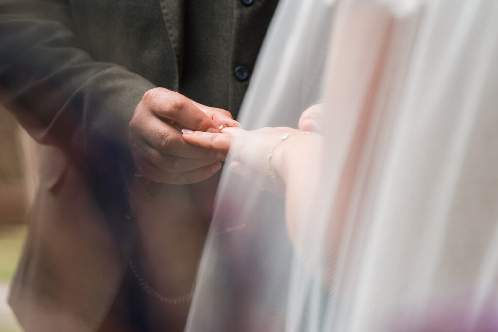 close up of groom placing wedding ring on brides hand