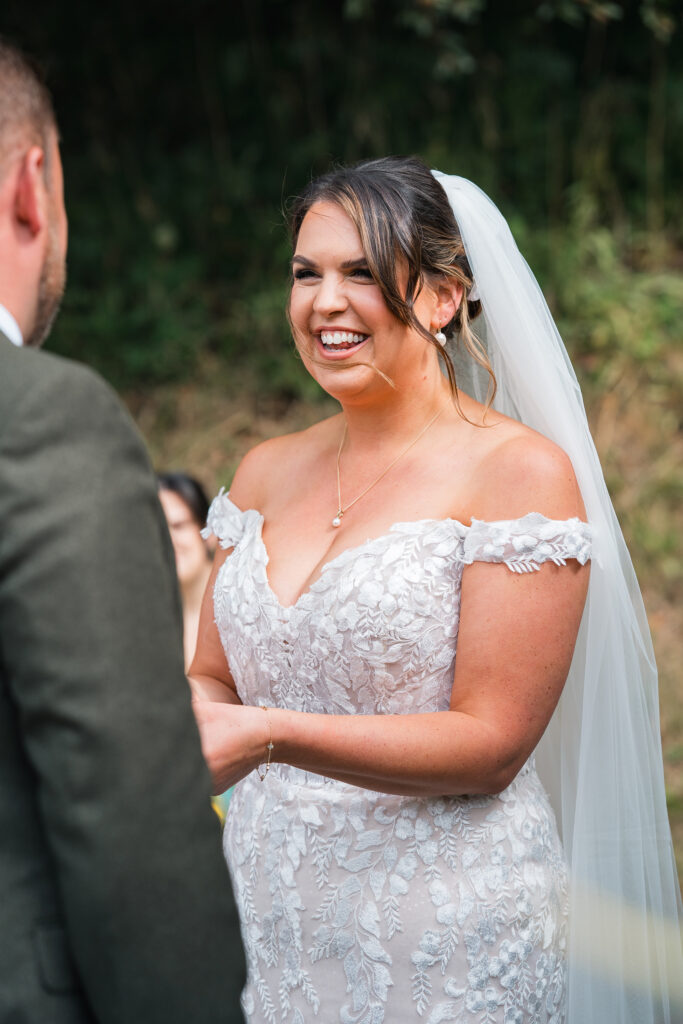 bride has a huge smile as she says vows at outdoor barn wedding