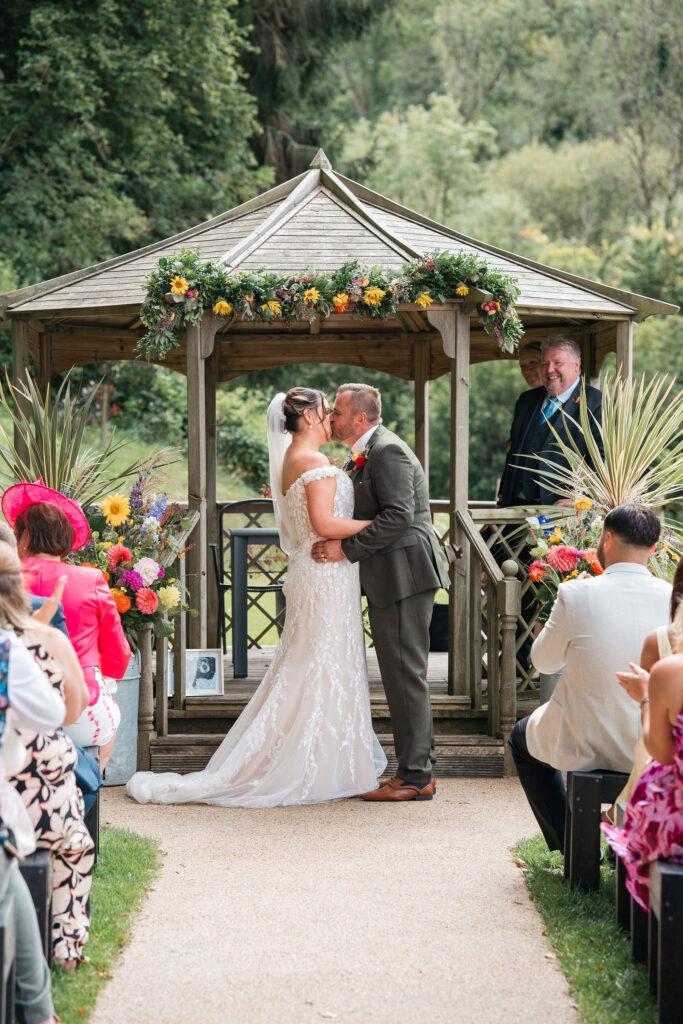 bride and groom share first kiss at the alter at Gorwell Farm outdoor wedding