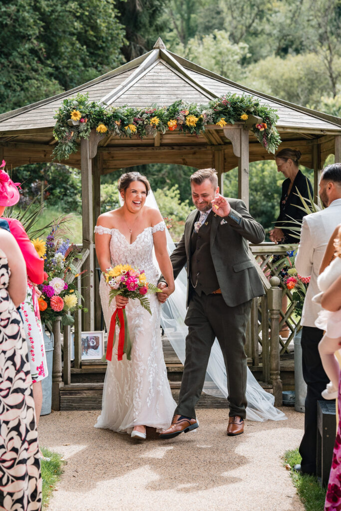 Groom dances in aisle as bride laughs at barn wedding