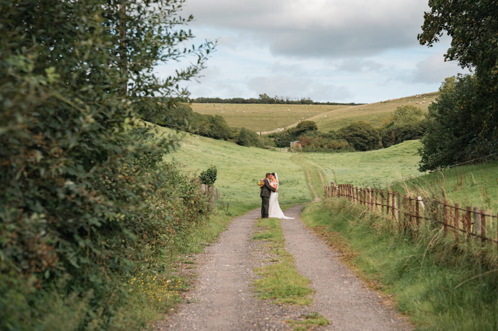 bride and groom embrace in hilly landscape during Gorwell Farm wedding photos
