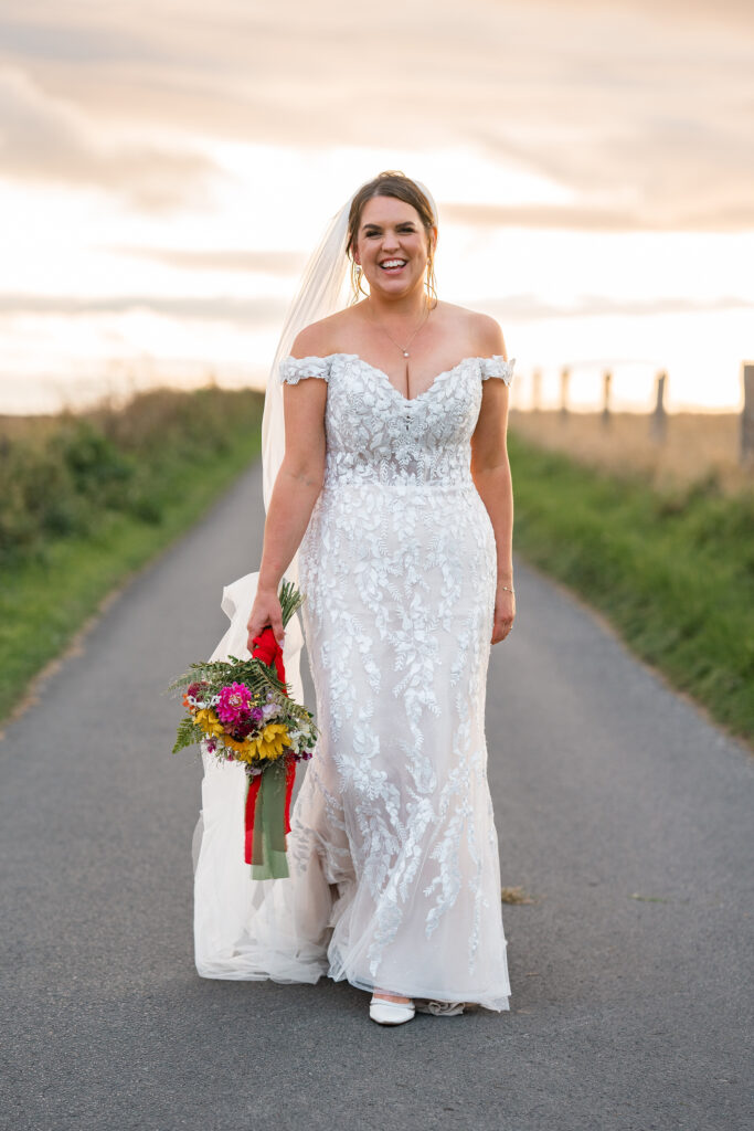 bride in lace sweetheart wedding dress smiles at camera at Gorwell Farm