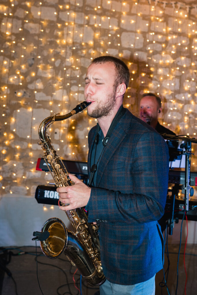 Saxophonist entertaining guests during wedding reception inside Gorwell Barn