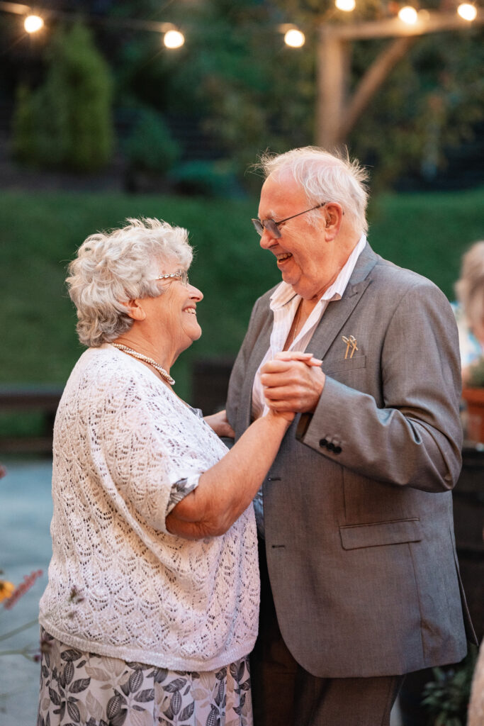 Brides grandparents dance and smile at each other at outdoor wedding reception