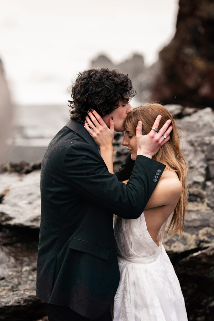 bride and groom embrace on black beach at Iceland Elopement