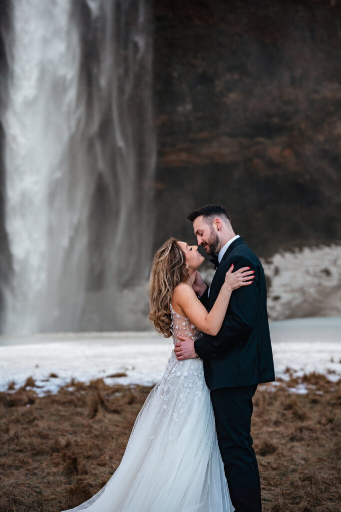 bride and groom kiss in front of Seljalandsfoss, Iceland waterfall